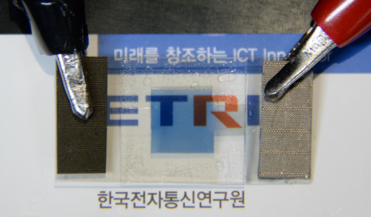 ETRI가 개발한 그래핀 기반의 투명 유연전극. 전기변색층이 착색된 후에도 밑바닥의 ETRI가 보일 정도로 투과도가 높다.  ETRI 제공